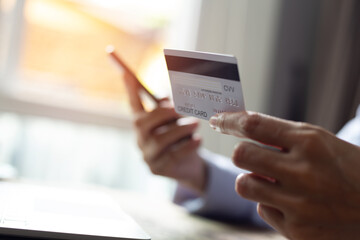 Woman hand holding credit card and using smart phone with laptop computer Online shopping concept