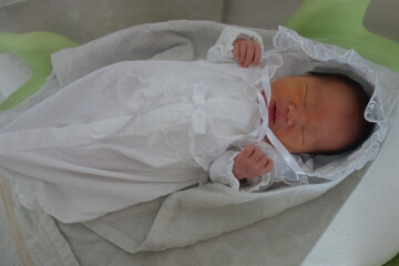 セレモニード゜レスを着て眠る生後4日目の新生児
