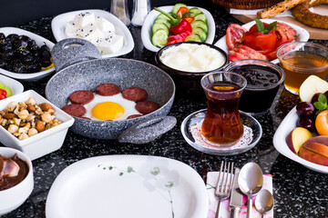 Fototapeta na wymiar Traditional Turkish Breakfast with sausage egg pan on granite marble table.Close and large view 