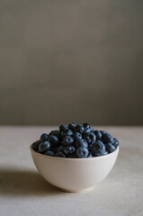 Fresh blueberry in ivory bowl on dark grey background. Freshness of sweet ripe berries