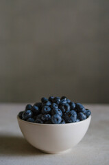 Fresh blueberry in ivory bowl on dark grey background. Freshness of sweet ripe berries