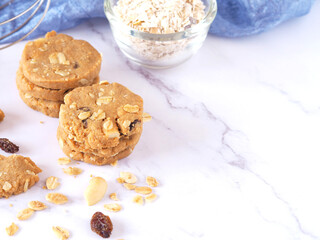 A pile of Healthy homemade oat cookies stacked on a marble table with a backdrop of blue fabric. Space for your text..