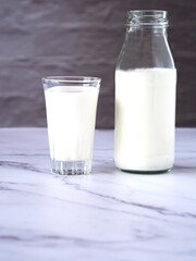 Fresh dairy products on a marble table and have a backdrop in the grey wall..