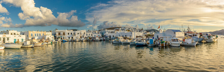 Fototapeta na wymiar Panorama view of the picturesque port in Naousa village with tradittional boats and whitewashed houses on Paros island, Greece. Taken on a beautifull afternoon with calm sea and amazing clouds 