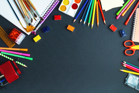 School supplies are displayed on a black Board background. copy space.