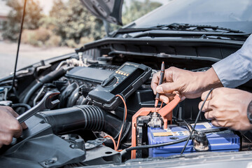 Auto mechanic using measuring equipment tool for fix checking car battery. Concepts of Old car repair service and insurance.