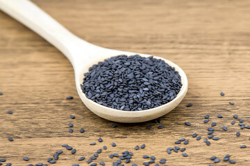 Black sesame seeds in a wooden spoon For healthy food and diet concepts.