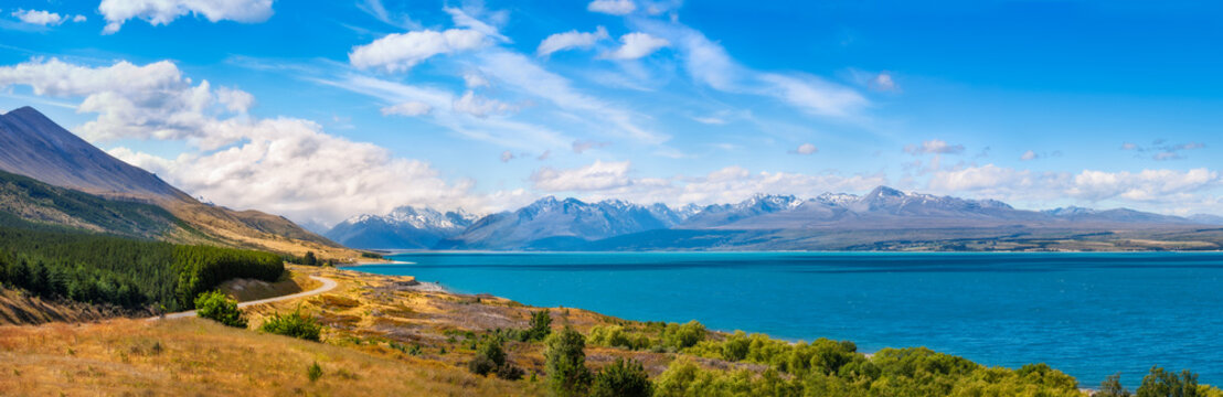Mount Cook Highway along Lake Pukaki, one of the most spectacular alpine scenery in the world in New Zealand, South Island on a beautiful summer day with snow-capped Mount Cook engulfed in the clouds.