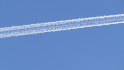 a trail of burned plane fuel high in the sky