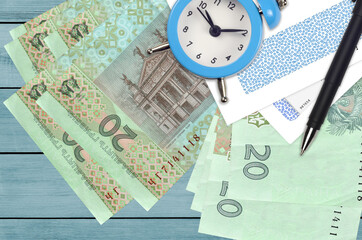20 Ukrainian hryvnias bills and alarm clock with pen and envelopes. Tax season concept, payment deadline for credit or loan. Financial operations using postal service