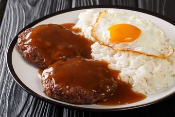 Loco Moco traditional Hawaiian dish of rice, ground beef patty and egg with gravy close-up on a plate. Horizontal