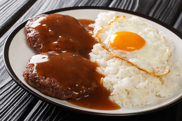 Loco Moco recipe is a delicious Hawaiian dish consists of white rice, a juicy hamburger patty, a fried egg, and brown gravy close-up on a plate. Horizontal