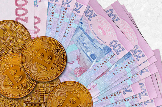 200 Ukrainian hryvnias bills and golden bitcoins. Cryptocurrency investment concept. Crypto mining or trading