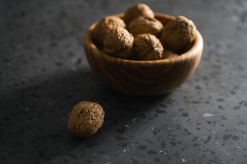 inshell walnuts in olive wood bowl on terrazzo countertop