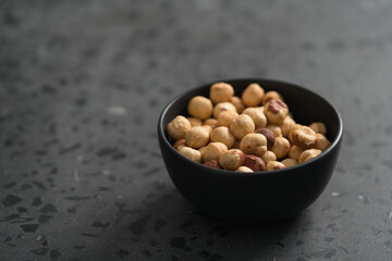 roasted hazelnuts in black bowl on terrazzo countertop