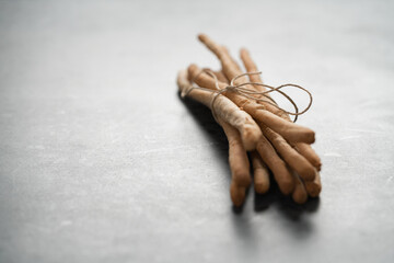 bunch of handmade wholegrain grissini tied with rope on concrete surface with copy space