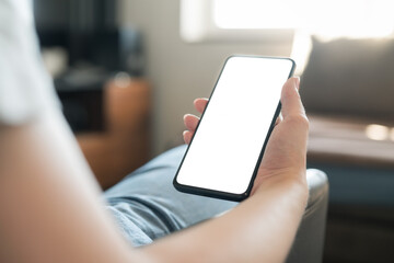 Young woman sitting in chair and holding smartphone with white screen