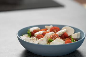 salad with mozzarella, tomatoes and lettuce in blue bowl
