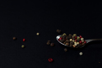 various types of pepper in a spoon on a dark background. hot seasonings for cooking.