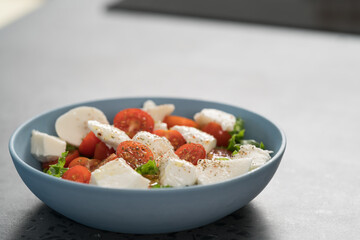 salad with mozzarella, tomatoes and lettuce in blue bowl