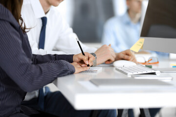 Business woman and man are discussing questions while using computer and blocknote in modern office, close-up. Teamwork in business