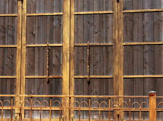 large wooden courtyard door and metal fence