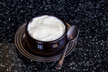 Natural,yogurt in casserole bowl on marble table with spoon.Close up taken