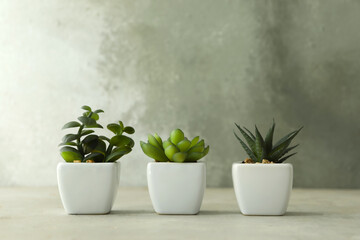 Artificial plants in white flower pots on light stone table