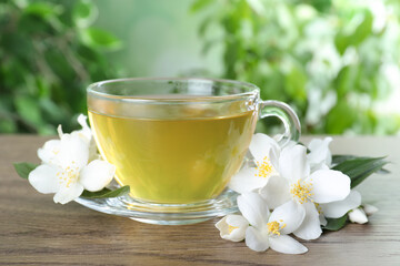 Obraz na płótnie Canvas Cup of tea and fresh jasmine flowers on wooden table