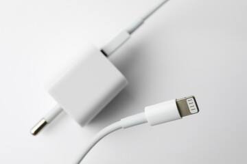 Charging cable and adapter on white background, top view