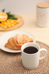 Cup of hot aromatic coffee and tasty croissant on table