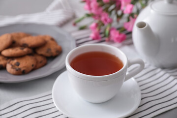 Cup of aromatic tea and tasty cookies on grey table