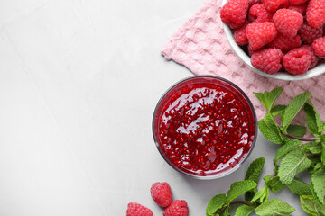 Delicious jam and fresh raspberries on grey table, flat lay. Space for text