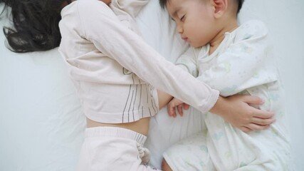 Asian sibling of sister and brother are sleeping together on the white bed in the morning time.