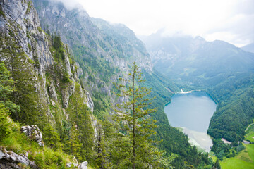 View to Leopoldsteinersee mountain lake surrounded by forest and steep limestone rock face in beautiful alpine landscape.