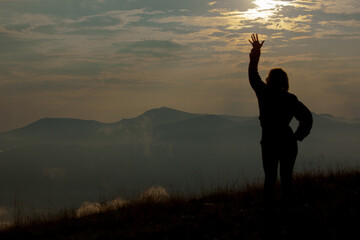 silhouette of a girl on a background of clouds sky in the mountains