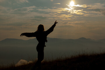 silhouette of a girl on a background of clouds sky in the mountains