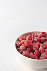Raspberries close-up in bowls on a white background, ripe juicy berries