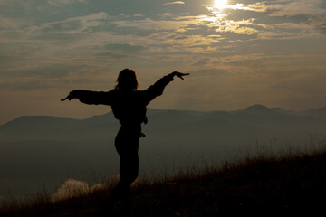 Fototapeta premium silhouette of a girl on a background of clouds sky in the mountains