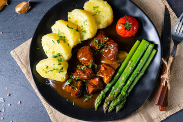 dumplings with beef goulash and green asparagus