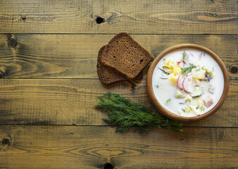 cold Russian okroshka soup with bread and dill on a wooden background 