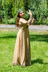 Armenian young woman in traditional clothes dancing in the forest