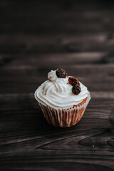 muffin with cream and raisins on a dark wooden background