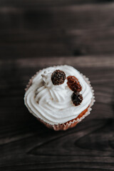 muffin with cream and raisins on a dark wooden background