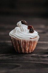 muffin with cream and raisins on a dark wooden background