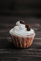 muffin with cream and raisins on a dark wooden background