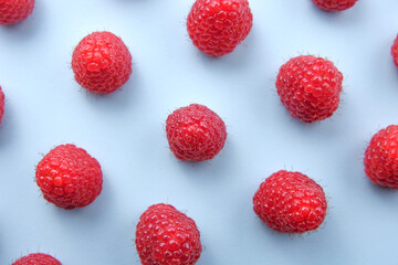Pattern of raspberry on blue background. Flat lay summer berries - red raspberries. Creative minimalism