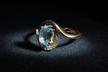 Gold ring with blue diamond on black background