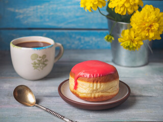 Lunch with strawberry donut and coffee in a light mug and a bunch of yellow flowers