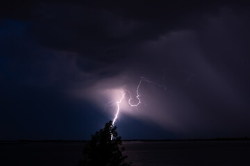 Naklejka na ściany i meble Lightning strikes at night over a huge river 